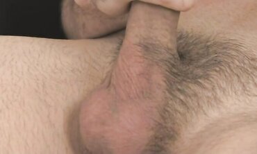 Fellow with shaven head globs his laundry and faps his chisel in dark-hued leather tabouret.