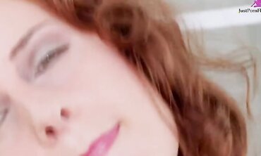Long curly haired red head with matching snatch, in red and black lingerie and stockings fucks herself with dildo on leather foot rest.