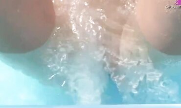 Red streaked brunette wearing a skull bikini gets off in jacuzzi on water jets and with large clear dildo.